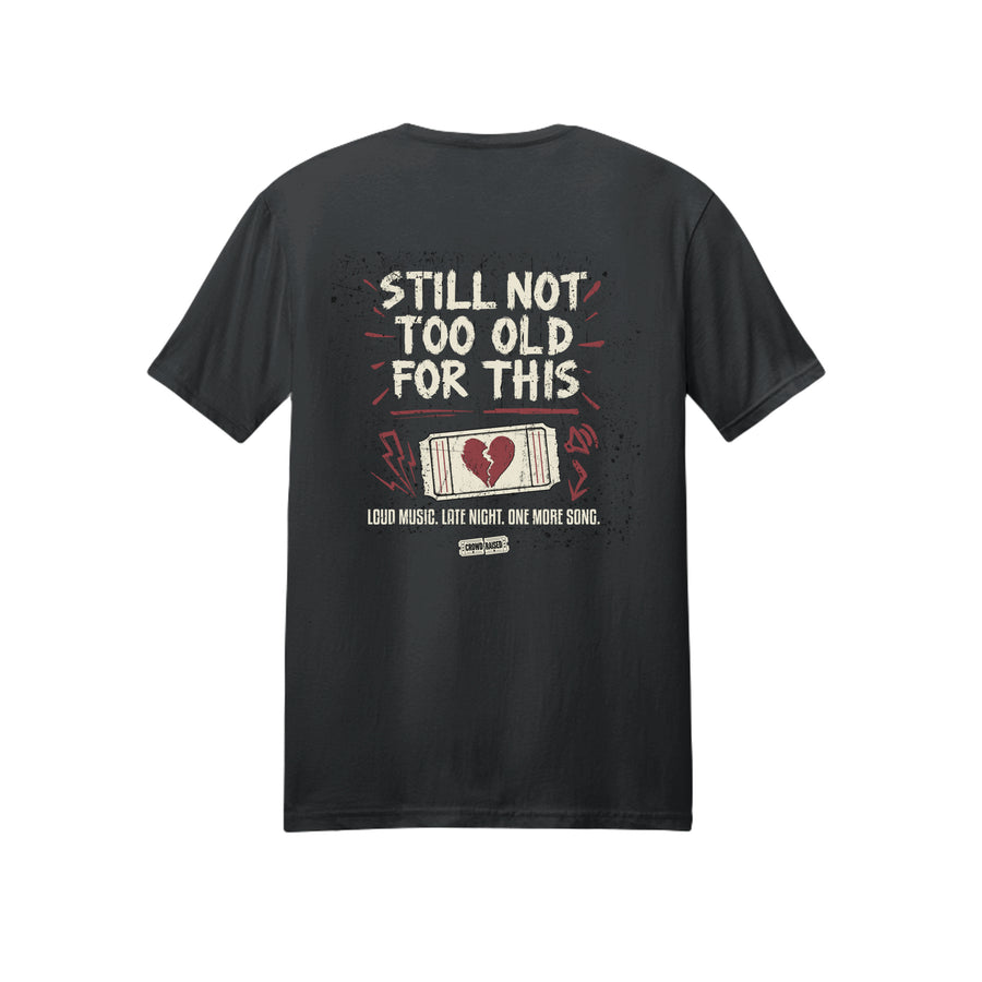 Back of black Crowd Raised T-shirt with cream “Still Not Too Old for This” lettering and a red and cream ticket graphic.